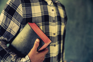 A young man holding a bible in his hands